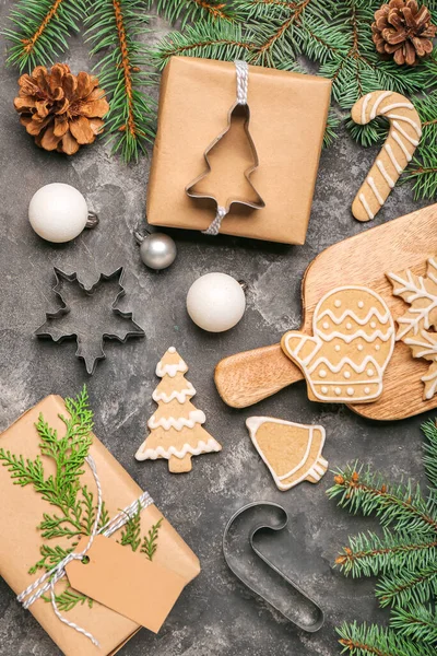 Composition with tasty Christmas cookies, gifts and fir branches on dark background