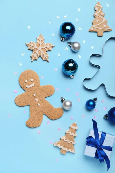 Composition with tasty Christmas cookies, gift and decorations on color background