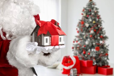 Noel Baba Noel için dekore edilmiş ev modelini elinde tutuyor. Gayrimenkul kavramı
