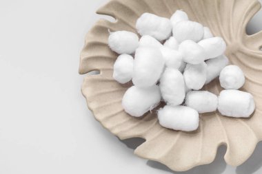 Gri zemin üzerinde yumuşak pamuk topları olan tabaklar