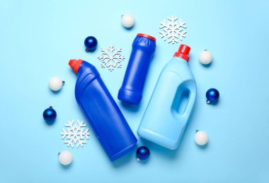 İçinde Noel topları ve mavi arka planda kar taneleri olan deterjan şişeleri.