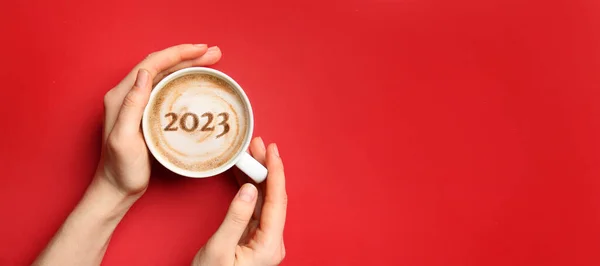女性的手与一杯热咖啡和图2023的红色背景与文字的空间 — 图库照片