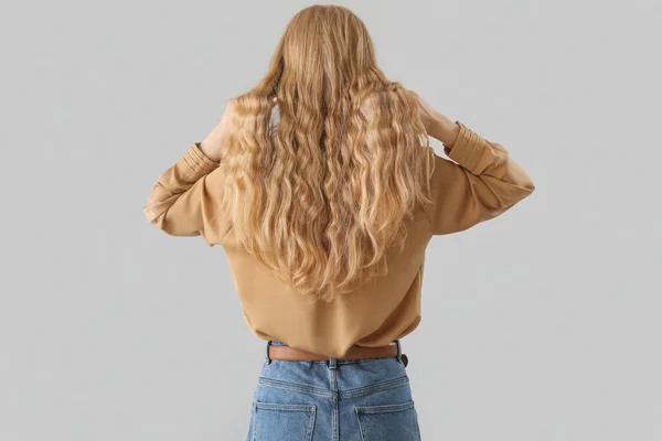 Женщина Трогает Блондинку Кудрявые Волосы Светлом Фоне — стоковое фото