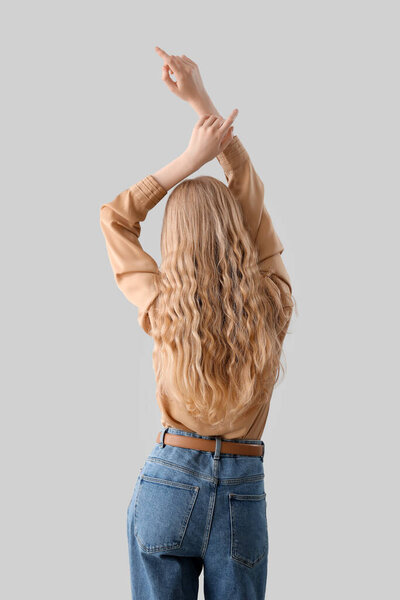 Young woman with beautiful curly hair on light background