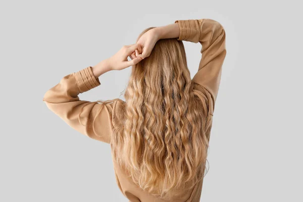 光の背景に美しい巻き毛の女性 — ストック写真