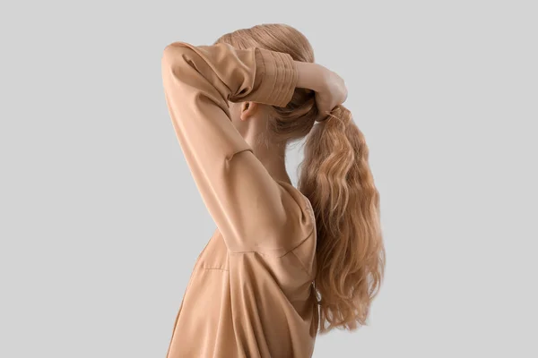Молода Жінка Тримає Кучеряве Світле Волосся Світлому Фоні — стокове фото