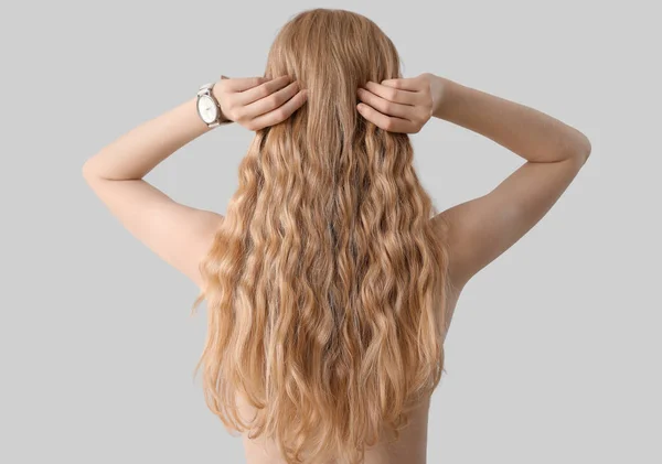 Junge Blonde Frau Berührt Lockiges Haar Auf Hellem Hintergrund — Stockfoto