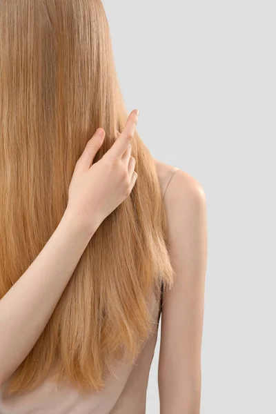 Ξανθιά Γυναίκα Αγγίζει Μακριά Μαλλιά Στο Φως Φόντο Closeup — Φωτογραφία Αρχείου