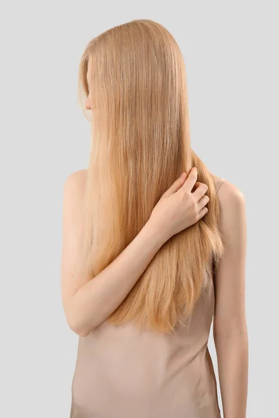 ブロンド女性タッチ長い髪上の光の背景 — ストック写真