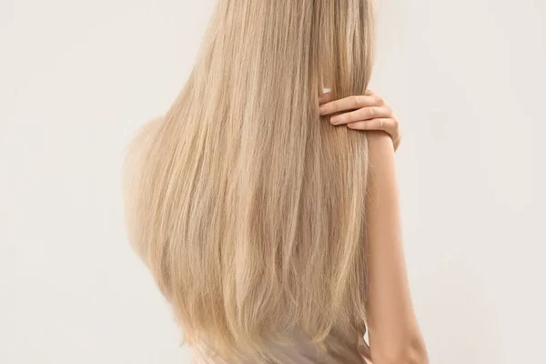 Kobieta Dotykając Blond Włosy Jasnym Tle — Zdjęcie stockowe