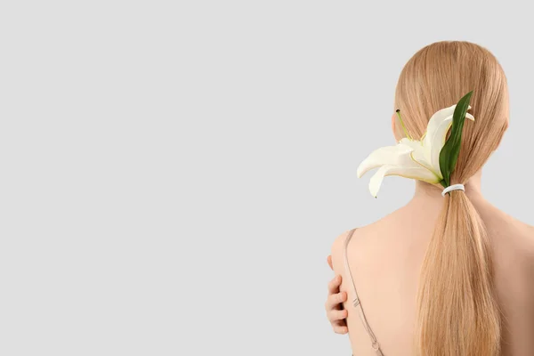 Blonde Frau Mit Pferdeschwanz Und Lilienblüte Auf Hellem Hintergrund — Stockfoto