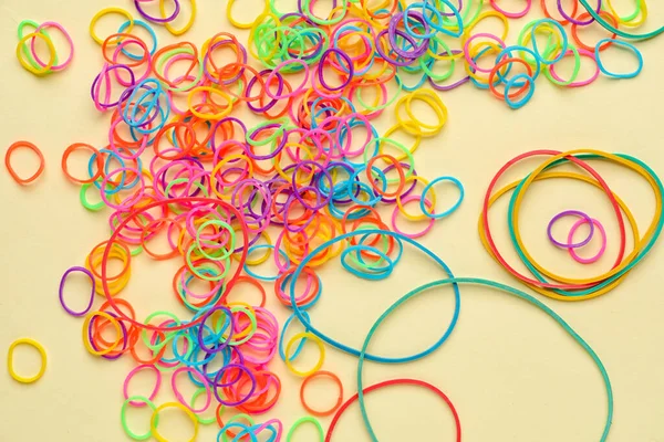 Heap of office colorful rubber bands on color background