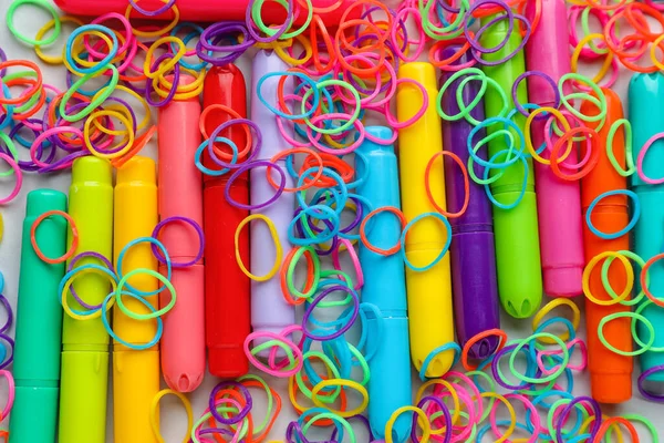 Colorful rubber bands and markers on white background, closeup