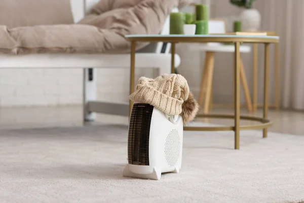 Modern electric fan heater with warm hat on carpet in living room
