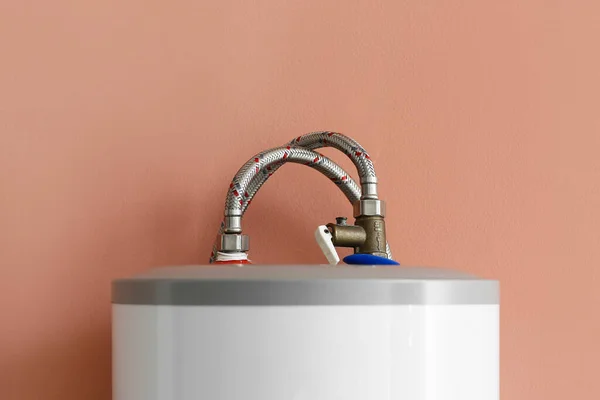 Modern electric boiler on color wall, closeup