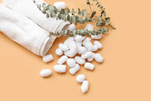 Soft cotton balls, towels and eucalyptus branches on beige background