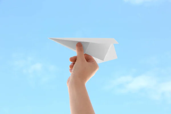 Woman with paper plane against blue sky, closeup