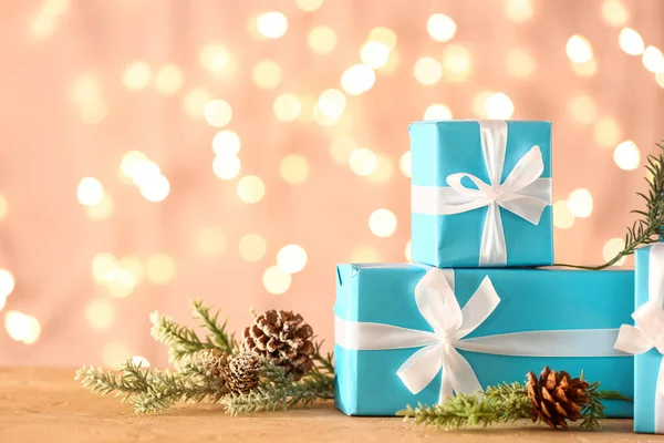 美しいクリスマスの贈り物とぼやけた光に対するテーブルの上の装飾 — ストック写真