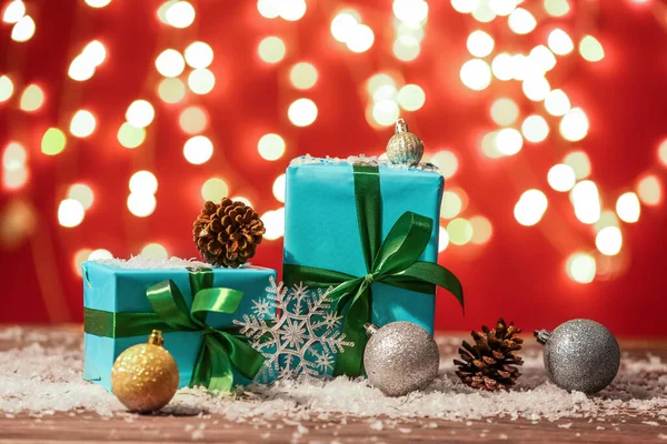 Weihnachtsgeschenke Dekoration Und Schnee Auf Dem Tisch Gegen Verschwommenes Licht — Stockfoto
