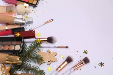 Beyaz arka planda Noel dalları olan makyaj ürünleri