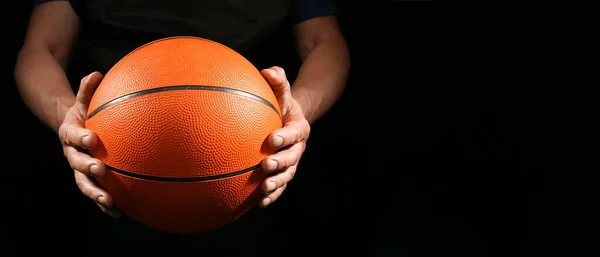 バスケットボール選手はテキストのためのスペースと暗い背景にゴムボールを保持 — ストック写真