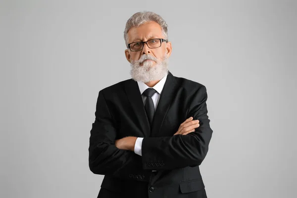 シニアひげそり男で眼鏡と黒スーツ上の灰色の背景 — ストック写真