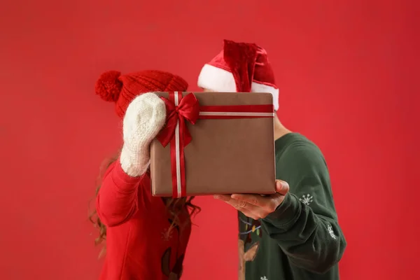 Kırmızı Arka Planda Noel Hediyesine Aşık Genç Çift — Stok fotoğraf
