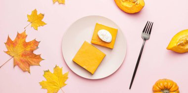 Lezzetli balkabağı turtası ve pembe arka planda sonbahar yapraklı tabak.