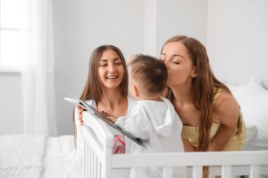 Mutlu lezbiyen çift ve yatak odasında kitabı olan küçük bebekleri