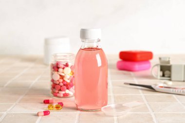 Öksürük şurubu ve boğaz ağrısı için haplar beyaz duvarın yanındaki masada, yakın plan.