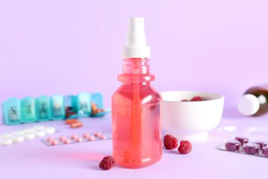 Boğaz ağrısı için sprey, haplar ve ahududu rengi arka planda, yakın plan