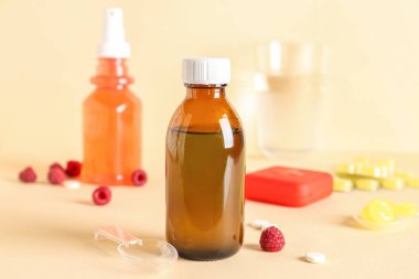 Kaşıklı öksürük şurubu, ahubu ve bej arka planda boğaz ağrısı için haplar.