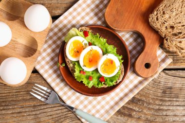 Ahşap zemin üzerinde kaynamış yumurta ile lezzetli tost tabağı
