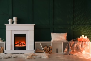 Karanlık oturma odasının içinde şöminesi, yanan mumları ve raf üniteleri var.