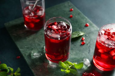 Koyu renkli arka planda soğuk nar suyu bardakları olan tahta, yakın plan.