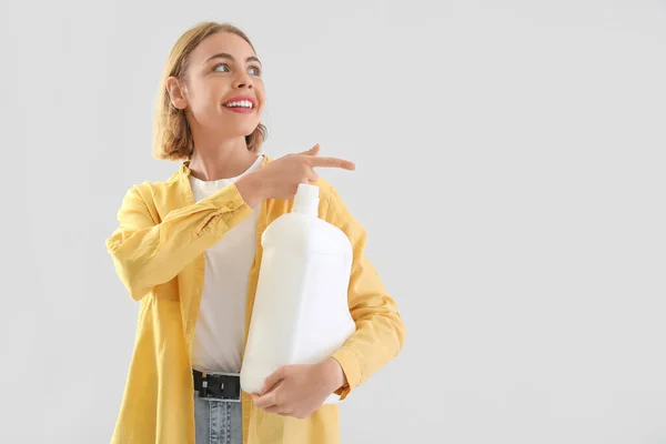 Ładna Kobieta Butelką Detergentu Wskazującą Coś Jasnym Tle — Zdjęcie stockowe