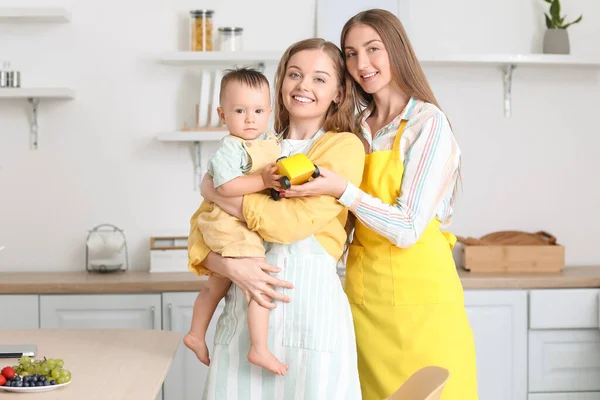 一对快乐的女同性恋夫妇和他们的小宝宝在厨房里玩玩具 — 图库照片