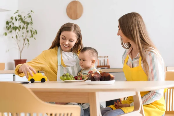 一对快乐的女同性恋夫妇带着他们的小宝宝坐在厨房的餐桌旁 — 图库照片