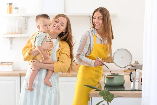 一对快乐的女同性恋夫妇带着他们的小宝宝在厨房做饭 — 图库照片
