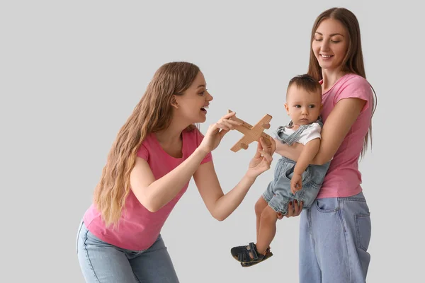 Feliz Casal Lésbico Com Seu Bebê Brinquedo Fundo Cinza — Fotografia de Stock
