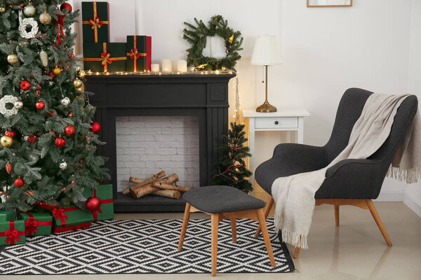 Interior of beautiful living room with mantelpiece, armchair and Christmas tree