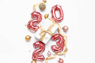 Şekil 2023 balonlardan, Noel hediyesinden, süslemelerden ve beyaz arka planda kurdeleden yapılmıştır.