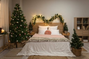 Parlayan Noel ağaçları ve köknar dallarıyla dolu yatak odasının içi