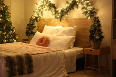 Parlayan Noel ağaçları ve köknar dallarıyla dolu yatak odasının içi