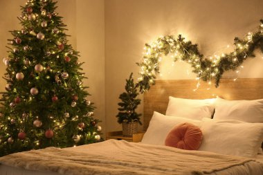 Parlayan Noel ağaçları ve köknar dallarıyla dolu yatak odasının içi
