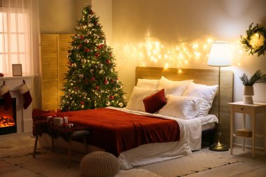 Parlayan ışıkları ve Noel ağacı olan yatak odasının içi.