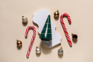 Dekoratif Noel ağacı, podyum, baston şekerler ve bej arka planda toplar