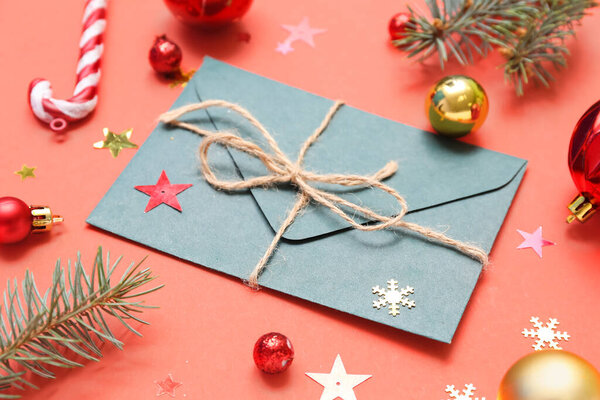 Composition with envelope, Christmas decorations and fir branches on red background, closeup