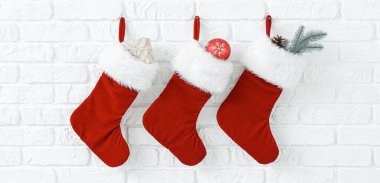 Beyaz duvarda asılı hediyeli Noel çorapları