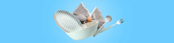 Flying clean tableware with napkin on blue background